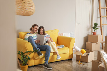 Poster - Young couple reading magazine in their new house on moving day