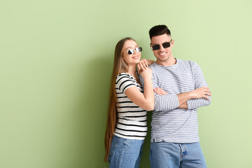 Poster - Young couple wearing stylish sunglasses on color background