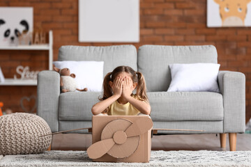 Wall Mural - Little girl playing with cardboard airplane at home