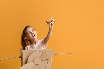 Sticker - Little girl playing with toy and cardboard airplane on color background