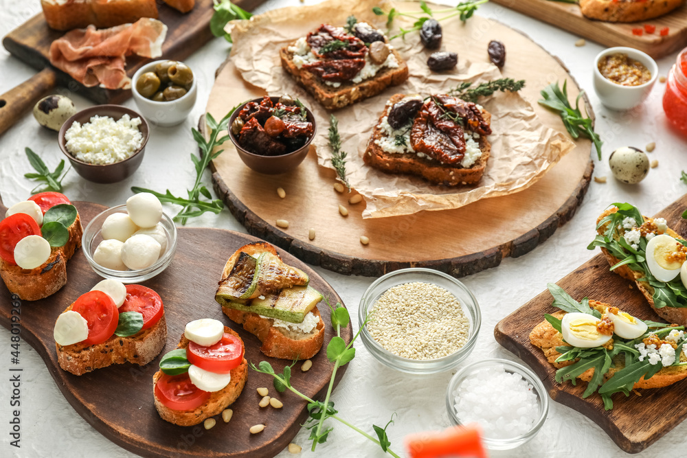 Composition with different tasty bruschettas and ingredients on light background, closeup