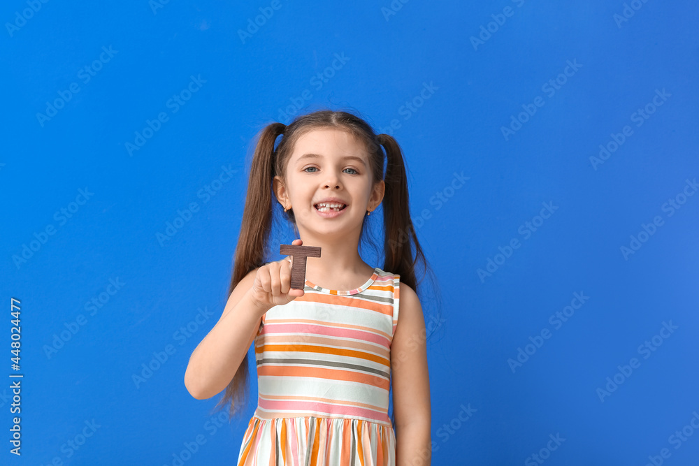 Little girl with letter T on color background