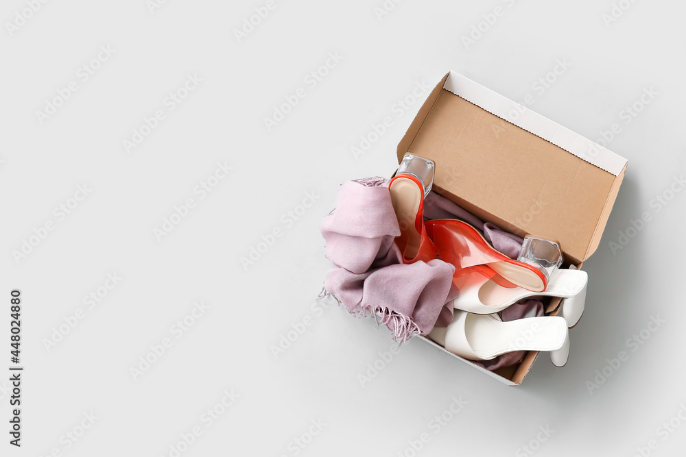 Wardrobe box with scarf and shoes on light background