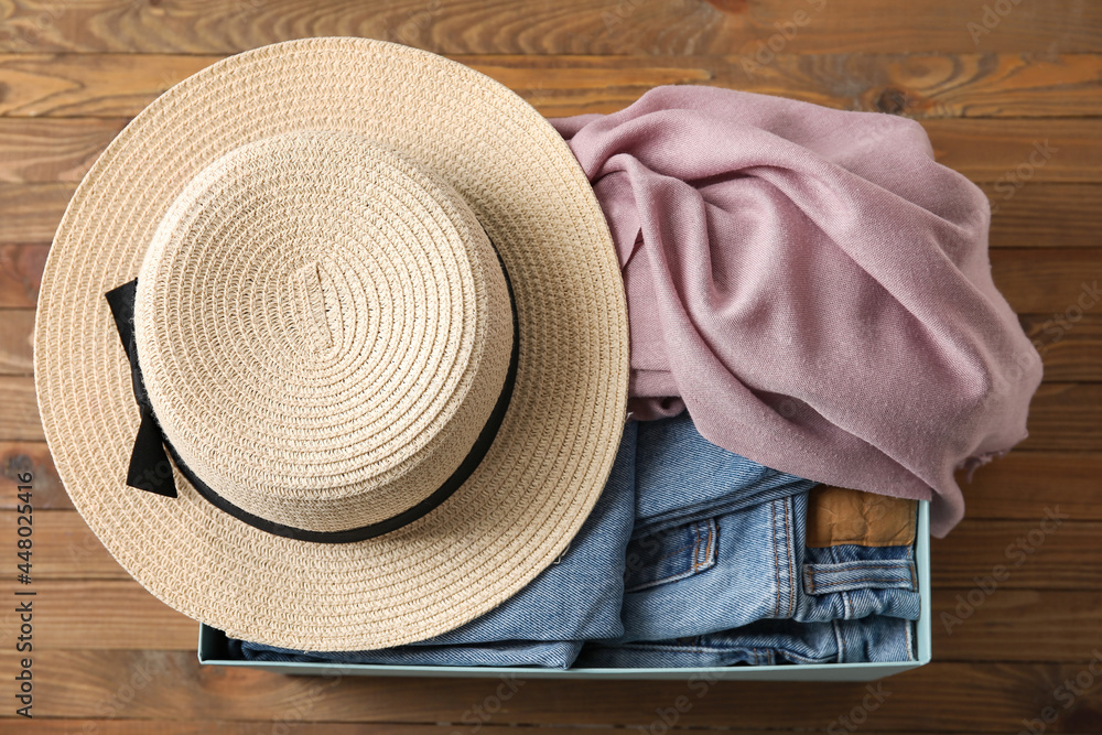 Wardrobe box with clothes and hat on wooden background