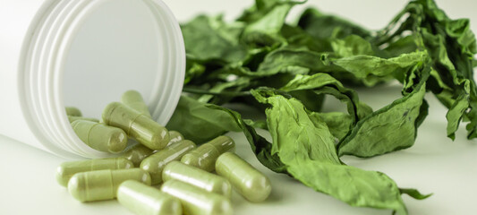 Herbal medicine capsules with Andrographis paniculata leaf on white background