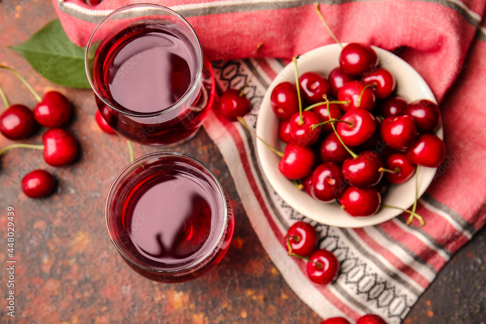 Composition with glasses of sweet cherry wine on grunge background