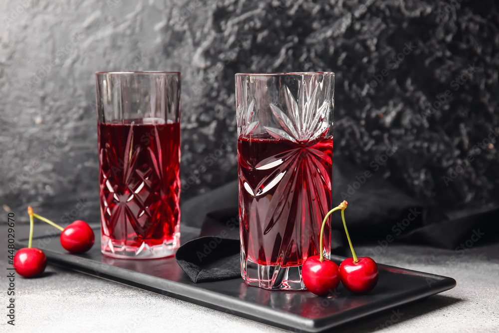 Glasses of sweet cherry wine on dark background