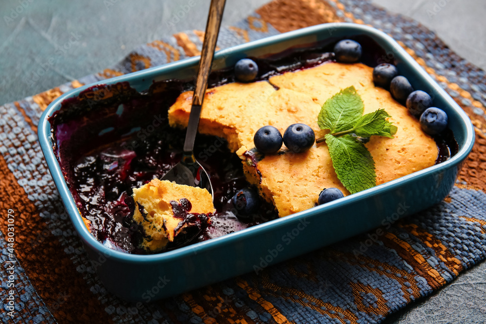 Baking dish with blueberry cobbler on dark background, closeup