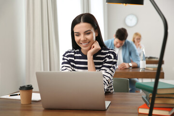 Poster - Young woman with laptop studying at table in library