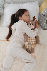 Canvas Print - Cute girl in pajamas sleeping with toy deer at home