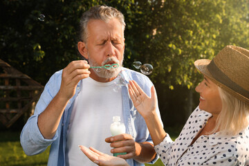 Sticker - Lovely mature couple spending time together in park. Man blowing soap bubbles