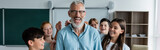 Fototapeta  - excited middle aged teacher laughing with closed eyes near happy multicultural pupils, banner