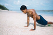 © BullRun - Man doing plank exercise on beach