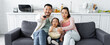 asian family watching tv and eating popcorn in living room, banner