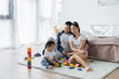 © LIGHTFIELD STUDIOS - cheerful asian parents looking at toddler daughter playing building blocks