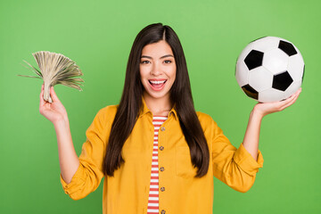 Wall Mural - Photo of impressed rich brown hairdo millennial lady hold money ball wear yellow shirt isolated on green color background