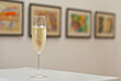 Glasses with wine on the background of the exhibition of paintings. Artwork blurred in the background. Art salon with white walls.