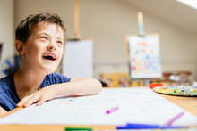 Cute Smiling Boy With Down Syndrome Playing With Paint At Painting Studio For Special Need Children.