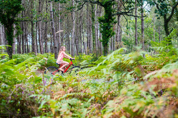 Wall Mural - cute little girl riding a bicycle in the forest