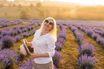 Young woman standing on a lavender field with sunrise on the background