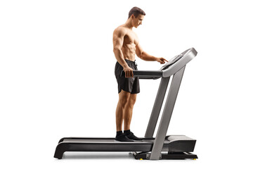 Sticker - Full length profile shot of a shirtless young man setting a program on a treadmill