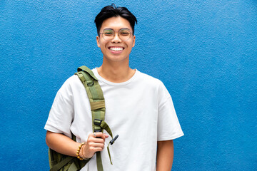 portrait of happy and smiling teen asian boy high school student looking at camera with backpack on 