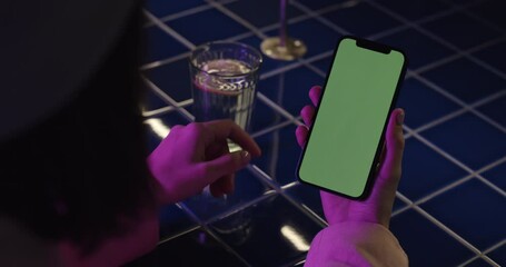Woman using smartphone with green screen at cafe