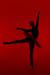 Wall Mural - Beautiful silhouette of ballerina on red background dancing ballet. Woman performs smooth movements with hands. Sensual dancer in tutu dress on scene under infrared light.. 