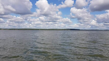 Wall Mural - Motor boat trip along the waves of the picturesque Senezh lake. Skyline, green trees on the shore and cloudy blue sky on a sunny day. Moscow region, Russia