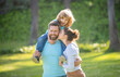 © Olena - Mother kiss father while boy child riding piggy back on fathers shoulders summer outdoors, family