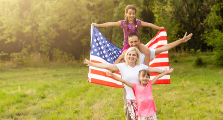 Wall Mural - happy family with the flag of america USA at sunset outdoors