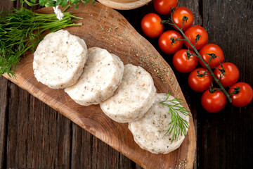 Wall Mural - Cod fish cutlets made of minced meat with breadcrumbs on a wooden cutting board. Rustic background. Top view