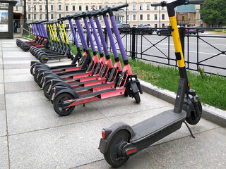 Electric scooters parked in a row on a city street are rented out. Ecological transport for movement. 