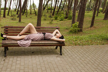 Young Beautiful Woman Lies On A Park Bench