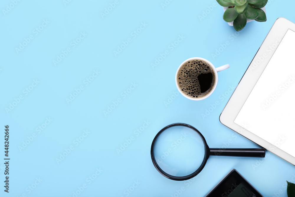 Cup of coffee, tablet computer and magnifier on color background