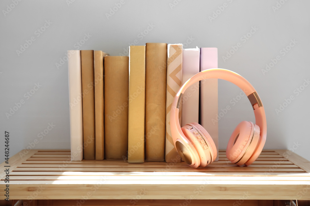 Headphones with books on shelf near light wall