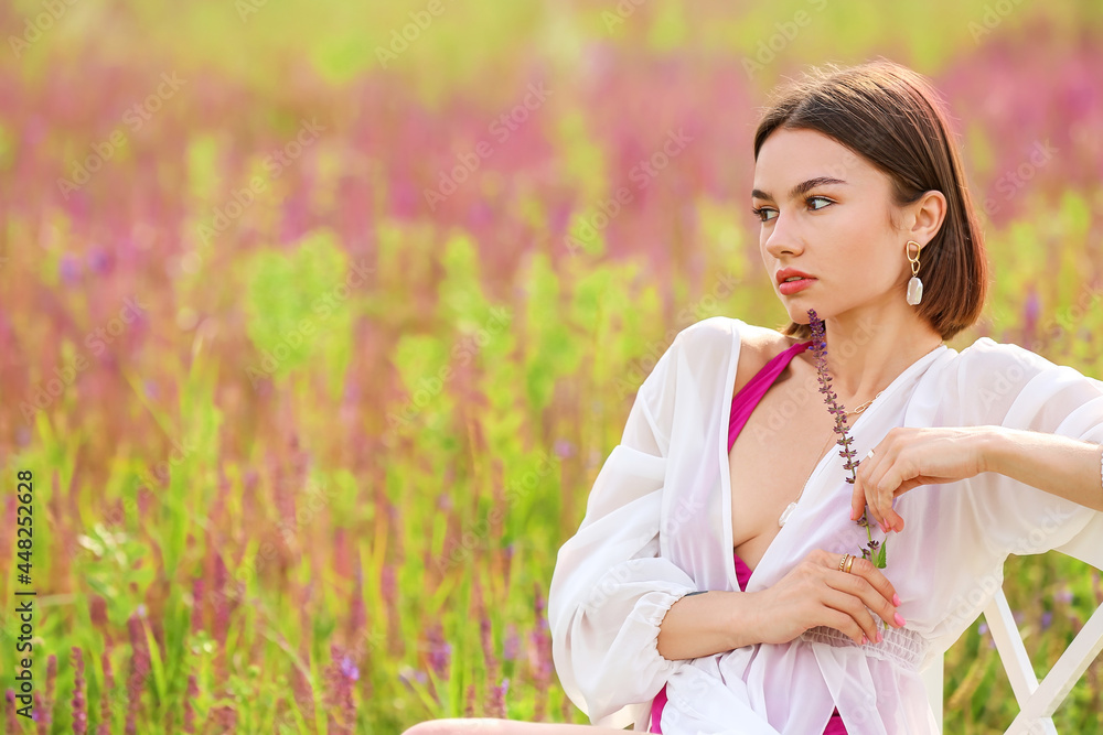 Beautiful young woman relaxing in blooming field