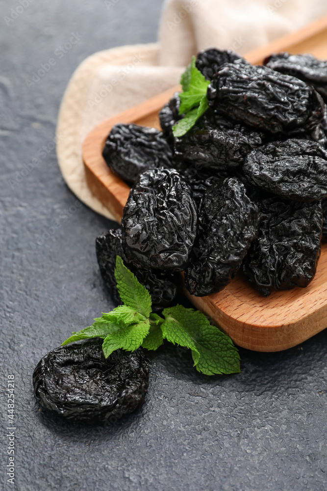 Board with tasty prunes on dark background, closeup