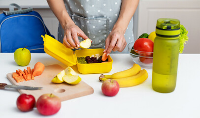 Wall Mural - Young woman making school healthy lunch in the morning.