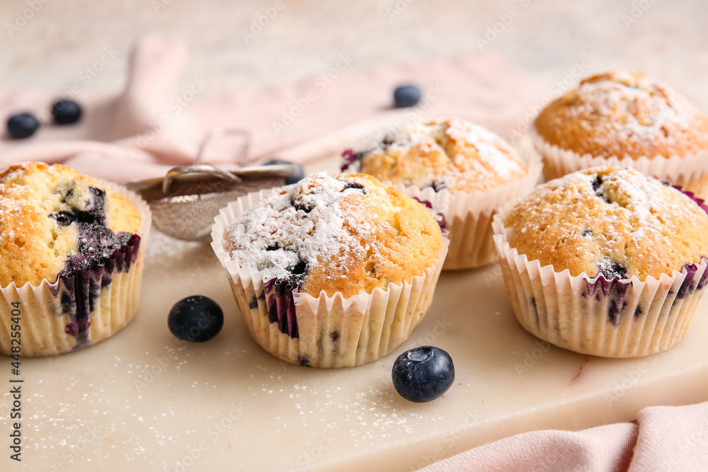 Board with tasty blueberry muffins on table, closeup