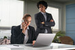 © ImageFlow - Businesswoman and businessman in formal suit are working together on laptop, talking smartphone. Office background. Concept of teamwork