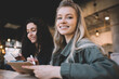 © BullRun - Smiling women taking notes and using tablet in modern cafe