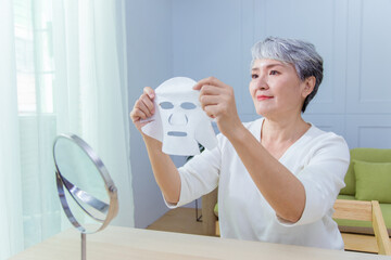 Senior Asia woman is doing the skin care with facial mask.