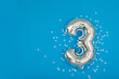 Silver balloon 3 on a blue background with confetti stars. Number three 3. Holiday Party Decoration or postcard concept with top view on blue background
