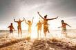 © cppzone - Big group of friends run and jump at sunset sea beach. Summertime holidays concept