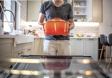 A Man Holding In His Hands Orange Enamel Dutch Oven.
