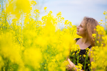 Poster - Blonde girl with luxurious long hair in a blooming rapeseed field of Ukraine