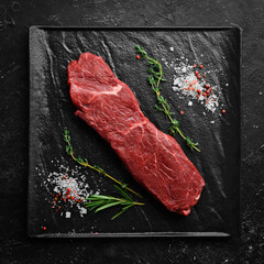 Wall Mural - Raw sirloin steak with thyme, rosemary and spices. Top view. Flat lay top view on black stone cutting table.