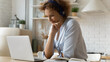 © fizkes - Happy woman in headphones using laptop, studying or working online at home in kitchen close up, smiling young female student watching webinar listening to lecture, distance education concept