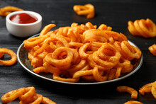 Golden Curly Fries With Ketchup On Rustic Plate